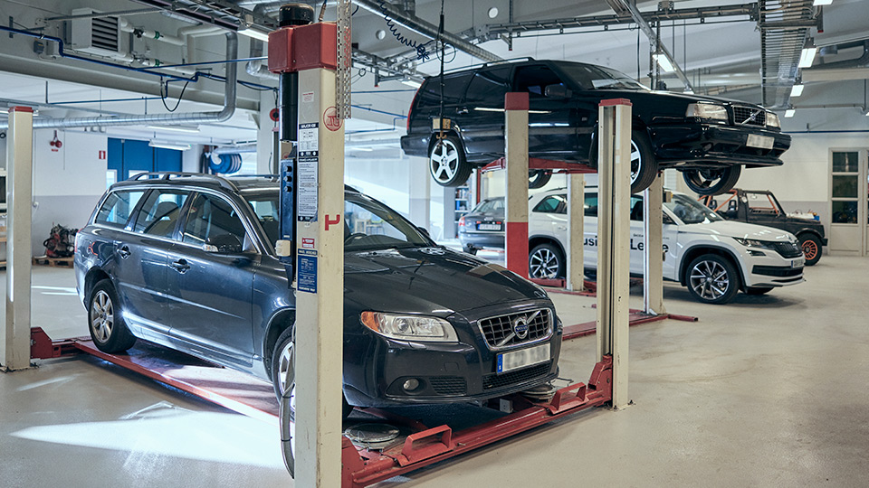 Fler personbilar varav två stycken står på liftar, en bil är högre upp.