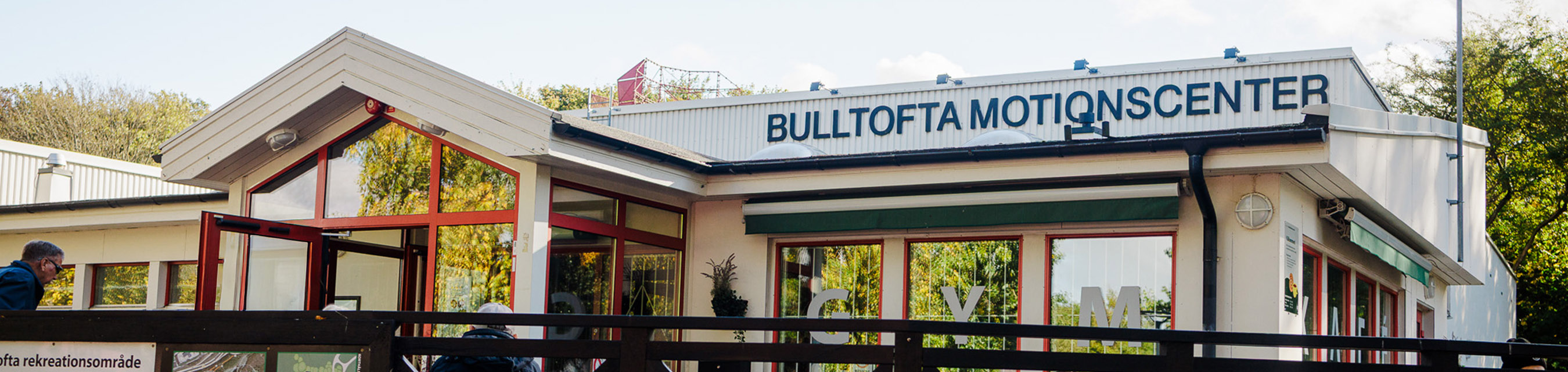 Bulltofta motionscenters fasad. I fönsterrutorna speglas träd.