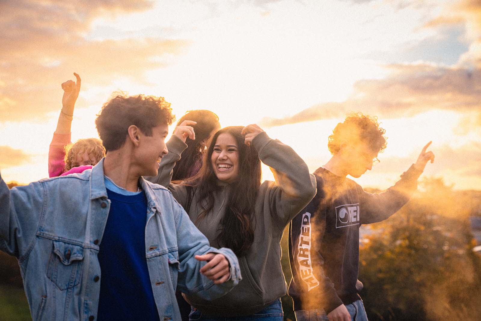 Glada ungdomar i solljus som tränger igenom moln.