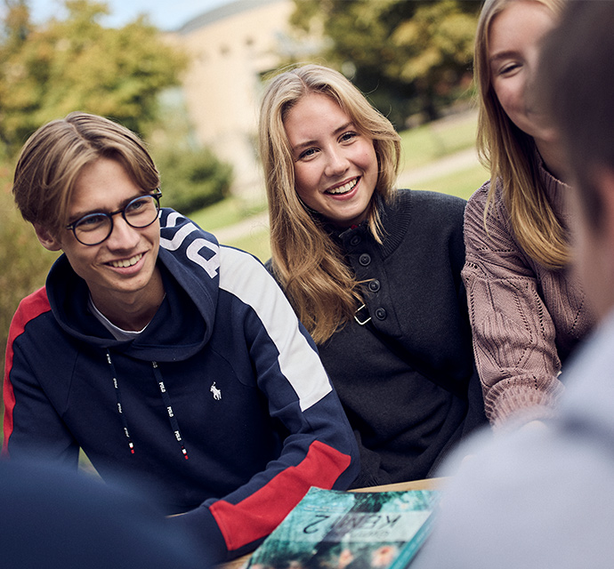 Elever i grupp på skolgården som snackar.