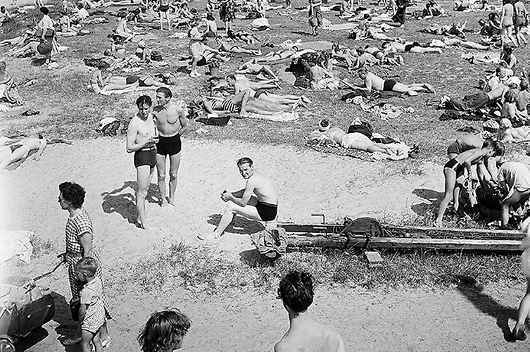 Äldre svartvitt foto. Strand fylld med badgäster.